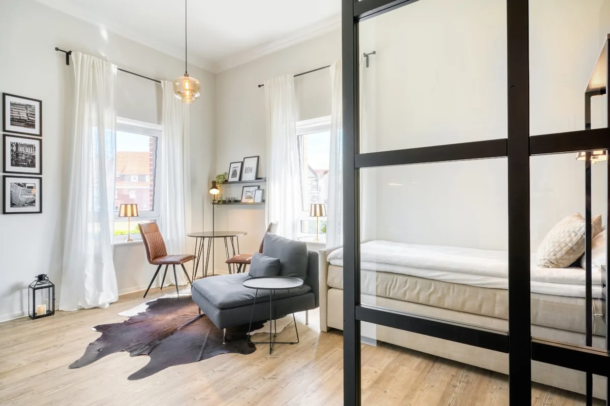 Apartment mit schwarzer Sprossen-Glaswand zwischen Wohnbereich und Schlafnische