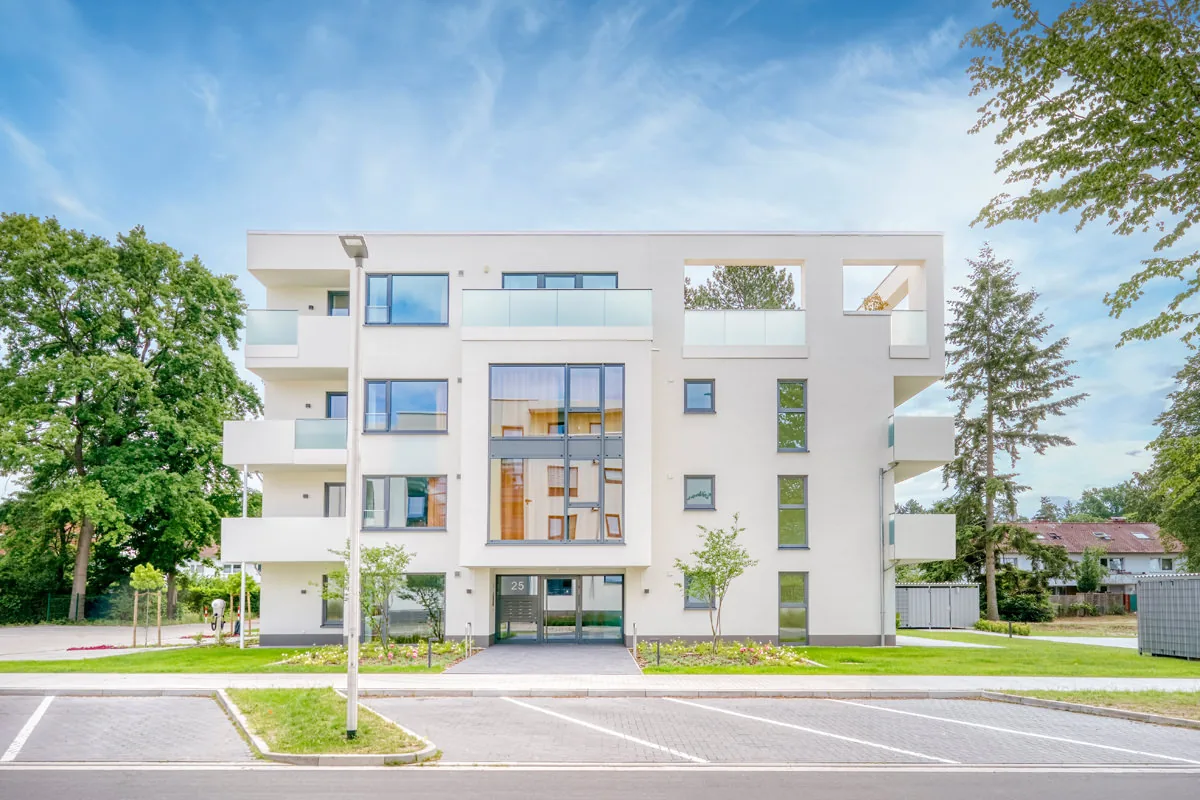 Außenansicht eines modernen Apartmenthauses mit umlaufenden Balkonen bei blauem Himmel