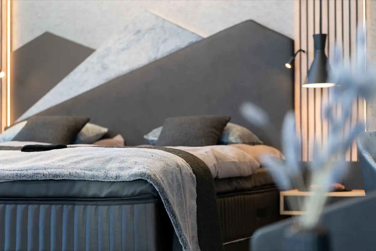 Close-up of a bed in front of a headboard as a mountain silhouette in grey and white