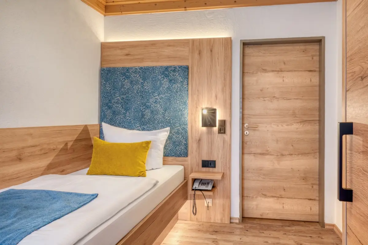 Single room in wood with a blue headboard and a yellow cushion