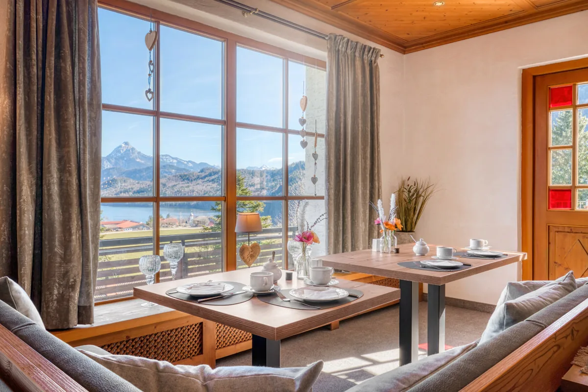 Frühstückstische am Panoramafenster mit Blick auf Bergkette und See