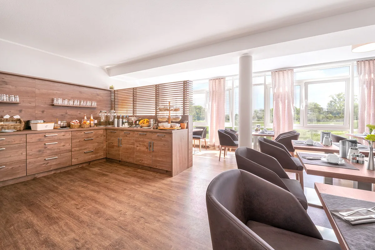 Frühstücksraum mit Buffetzeile aus Holz, Säule und Fensterfront mit rosa Vorhängen