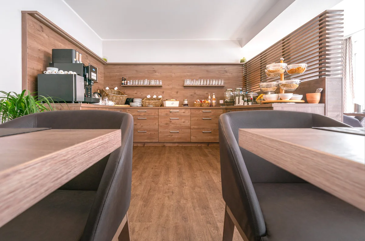 Buffetzeile aus Holz im Frühstücksraum, im Vordergrund zwei hohe Stuhllehnen