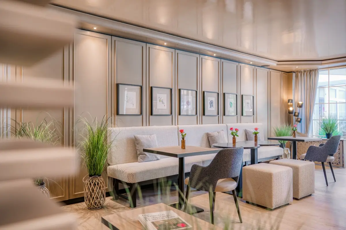 Bright breakfast and lounge area with long benches and a row of pictures