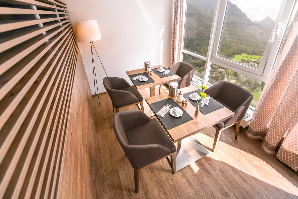 Blick von oben auf zwei eingedeckte Tische am Panoramafenster mit Bergblick