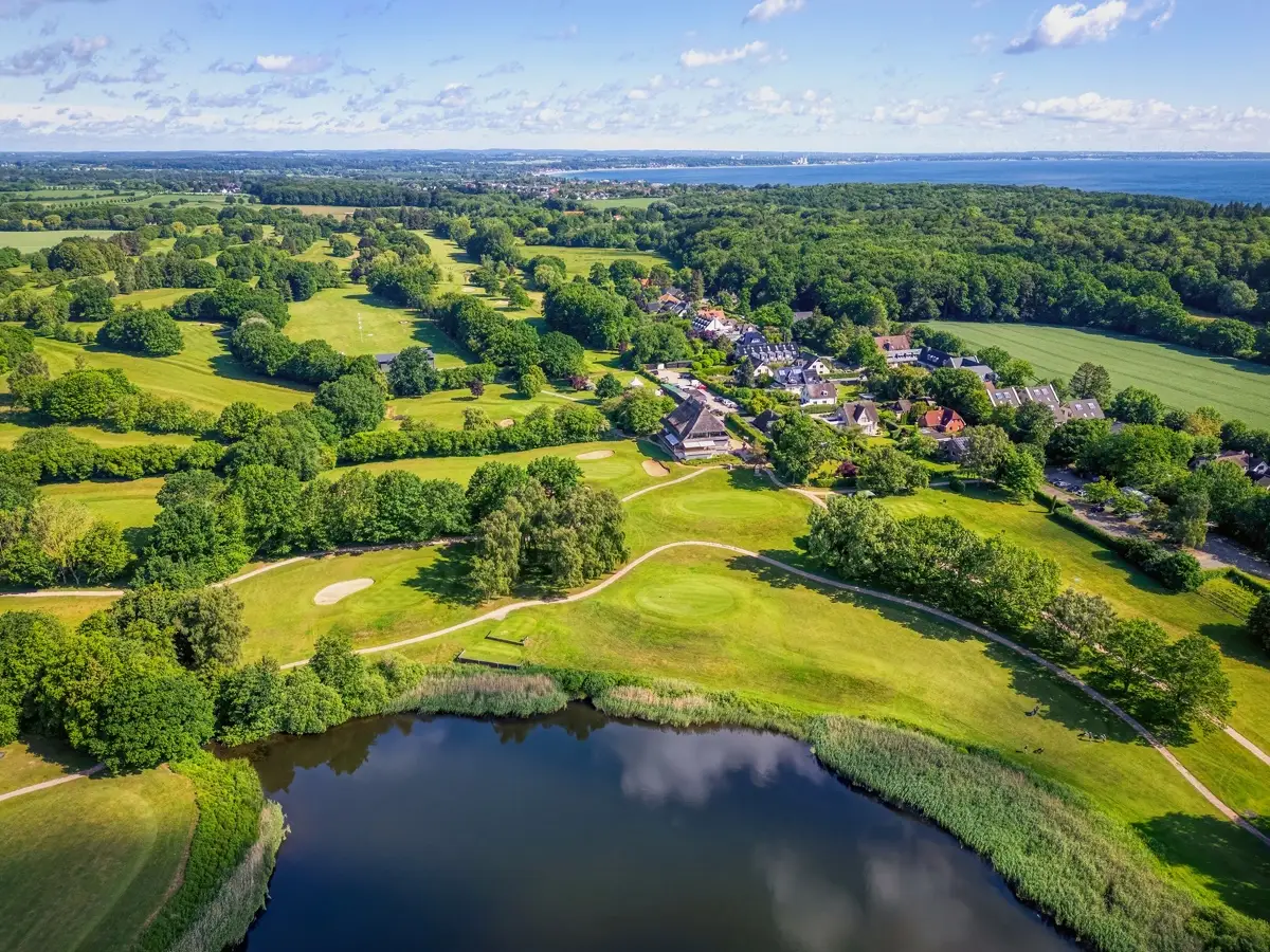 Aerial view of a coastal golf course with the Bay of Lübeck behind it