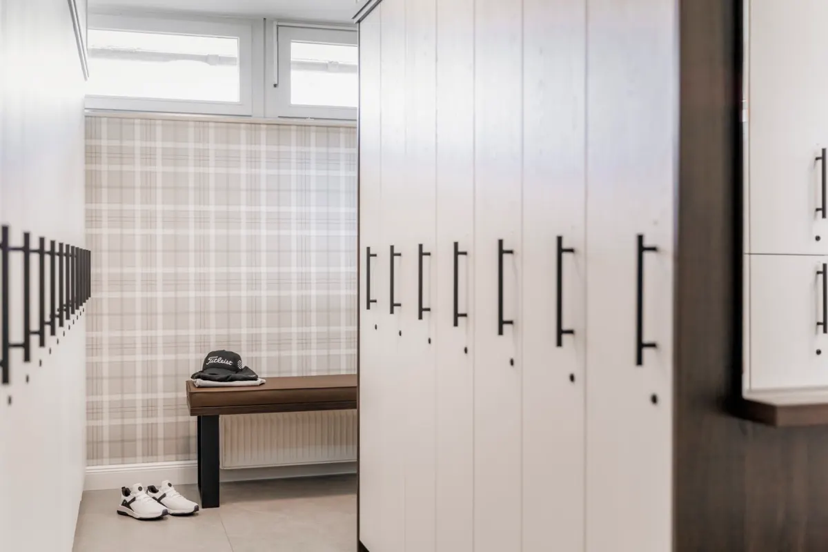 Golf changing room with pale lockers, a bench, a cap and golf shoes