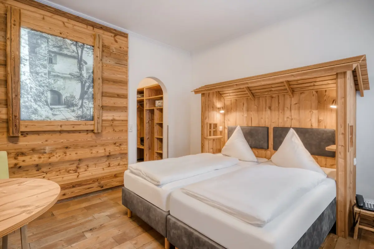 Hotel room with an old-timber wall and a double bed under a wooden canopy