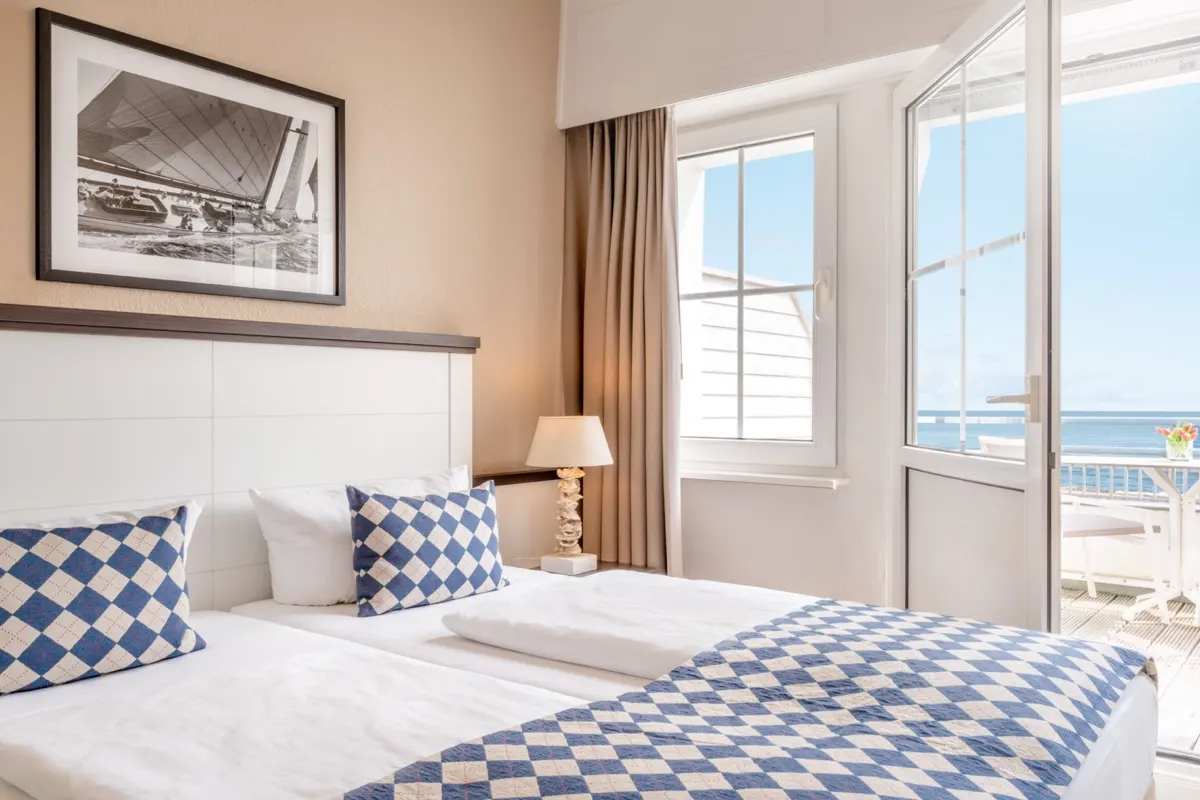 Double bed in front of an open balcony door with a sea view