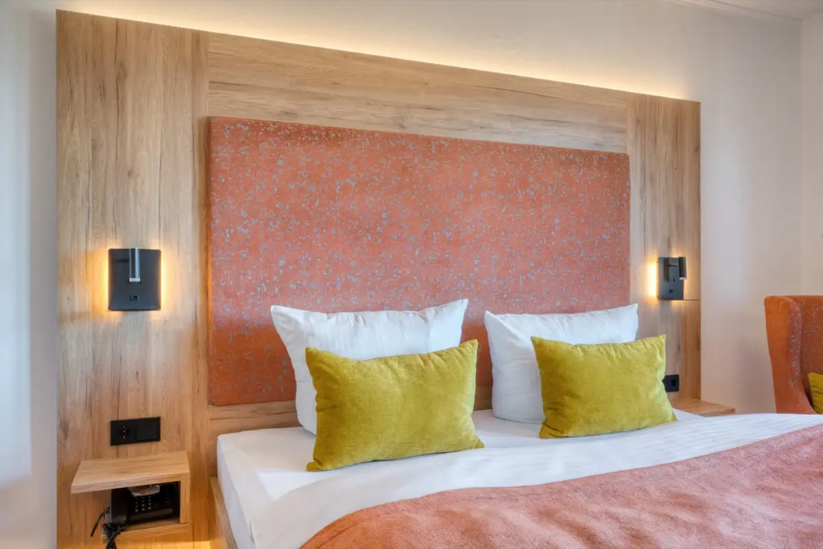 Double bed with an orange headboard and reading lamps
