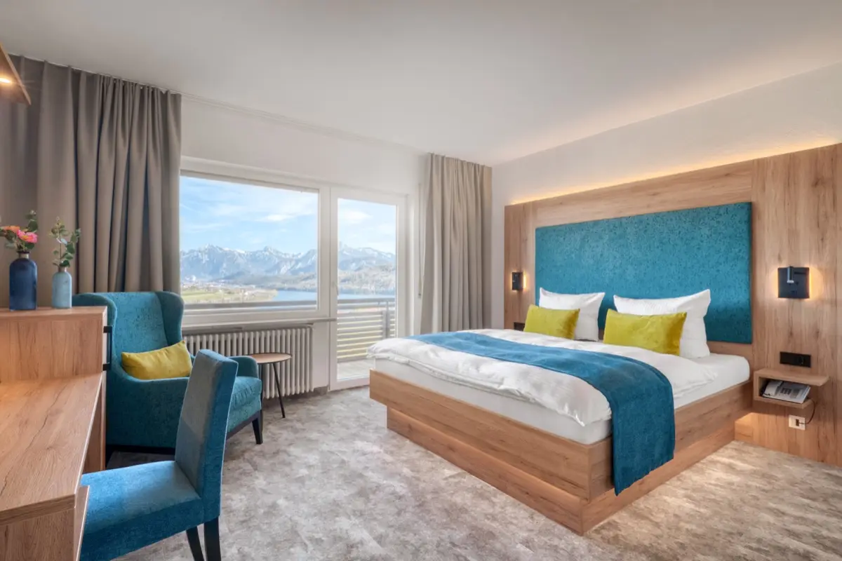 Hotel room with a double bed, armchair and a window to the mountains