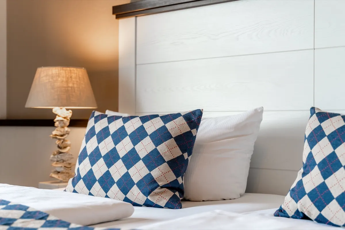 Close-up of blue and white checked cushions on a made-up bed