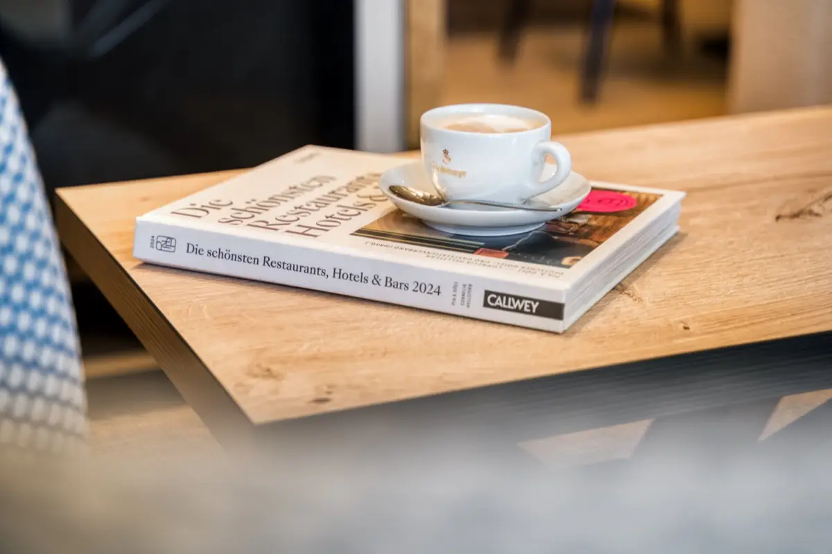 Coffee cup on a book about restaurants, hotels and bars on a wooden table