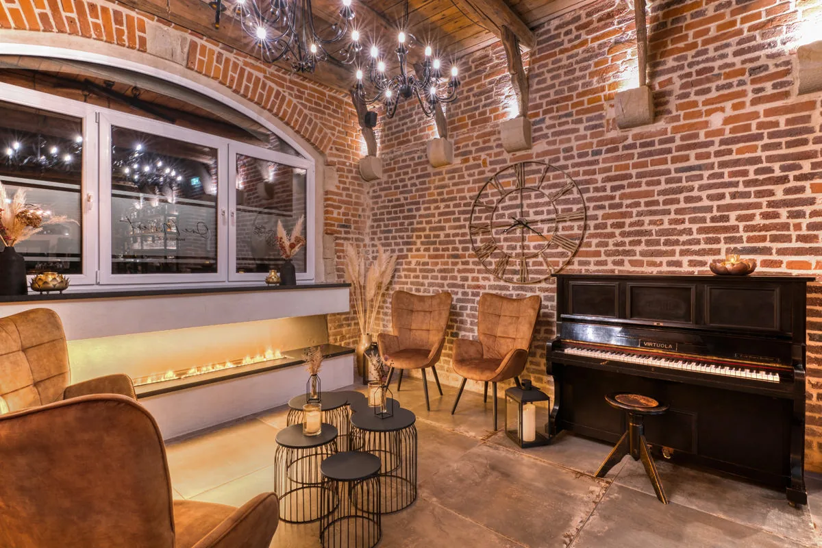 Lounge mit Backsteinwand, Klavier, langem Kamin und Ohrensesseln