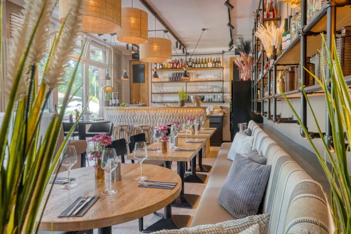 Restaurant with wicker pendant lights, pale bench seating and a bar behind