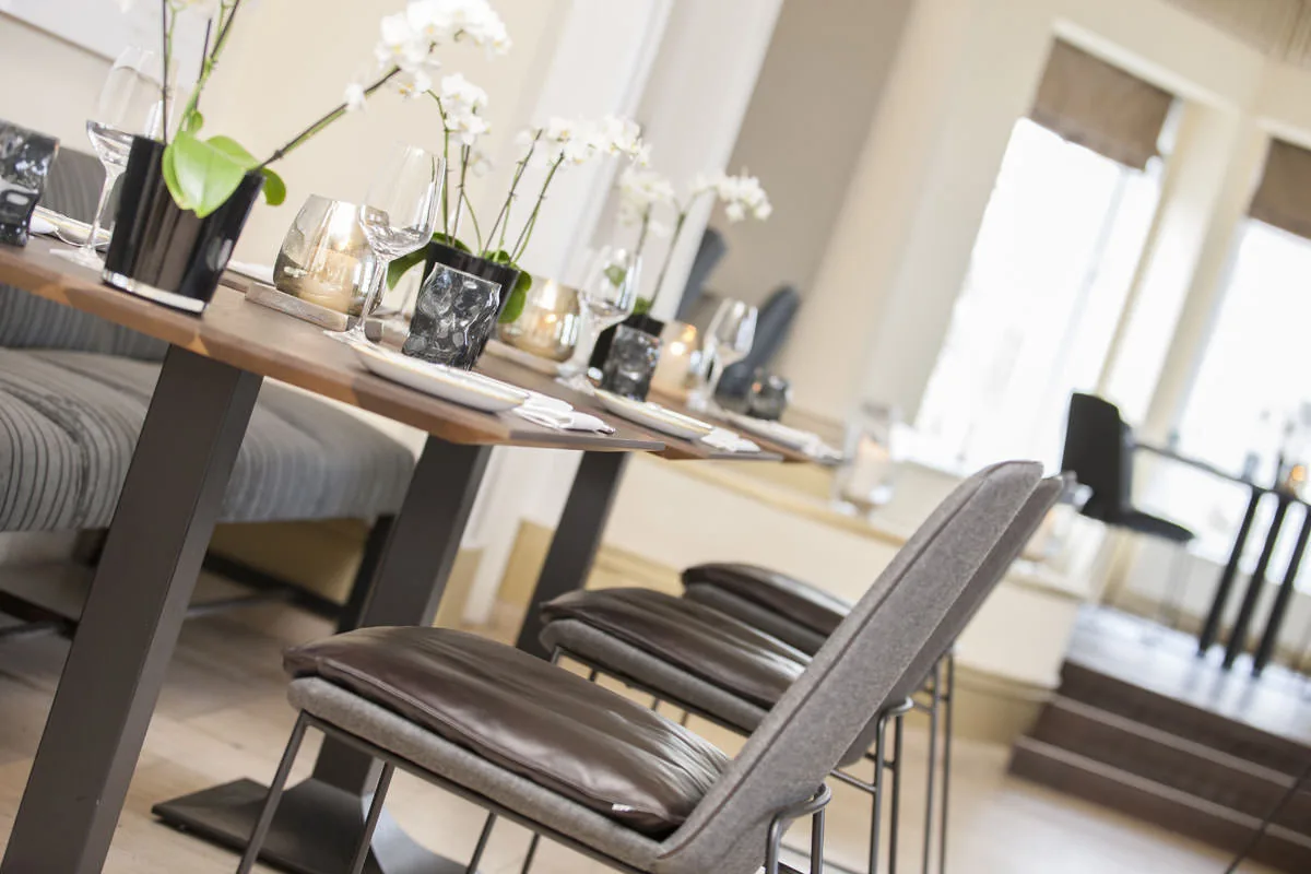Lange Tafel mit Orchideen und Windlichtern, davor eine Reihe Lederstühle