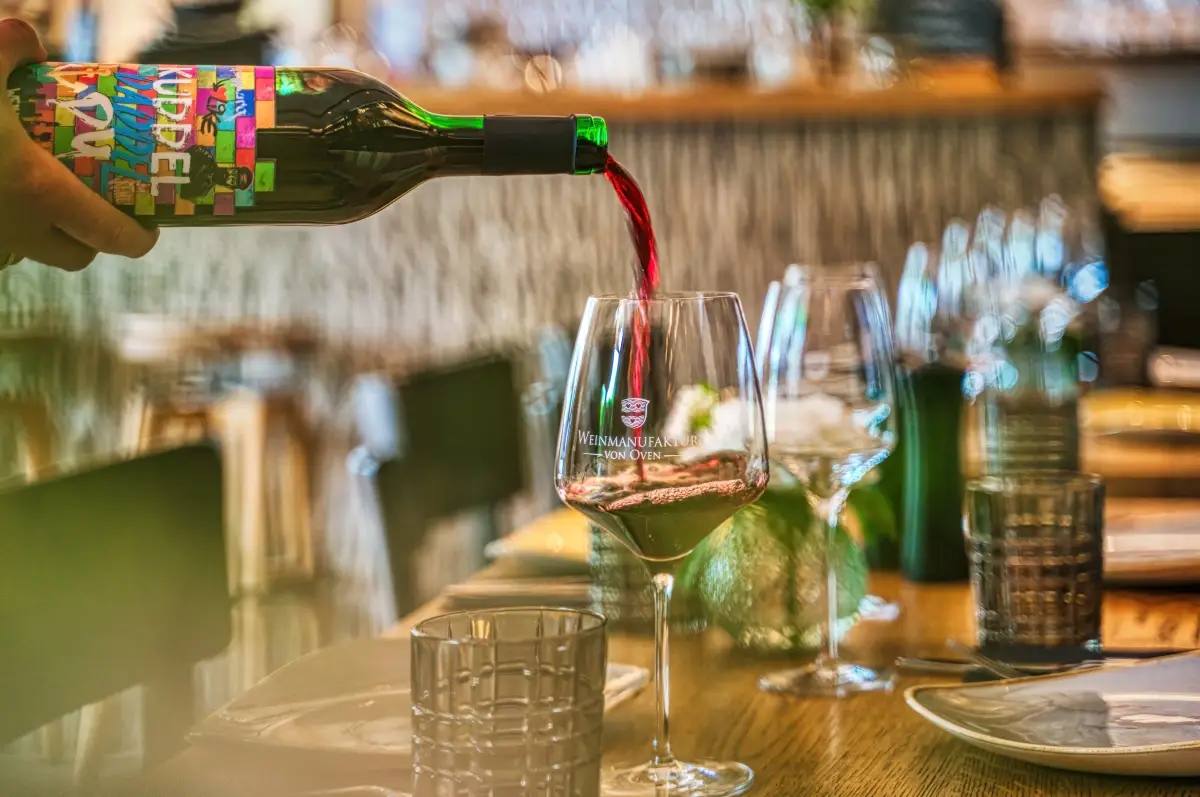 Red wine being poured into a glass at a laid table