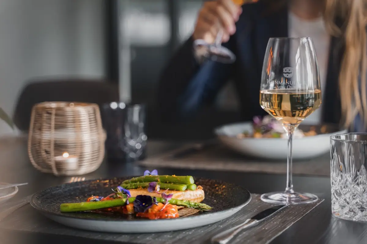 Plated fish with green asparagus, a glass of white wine beside it