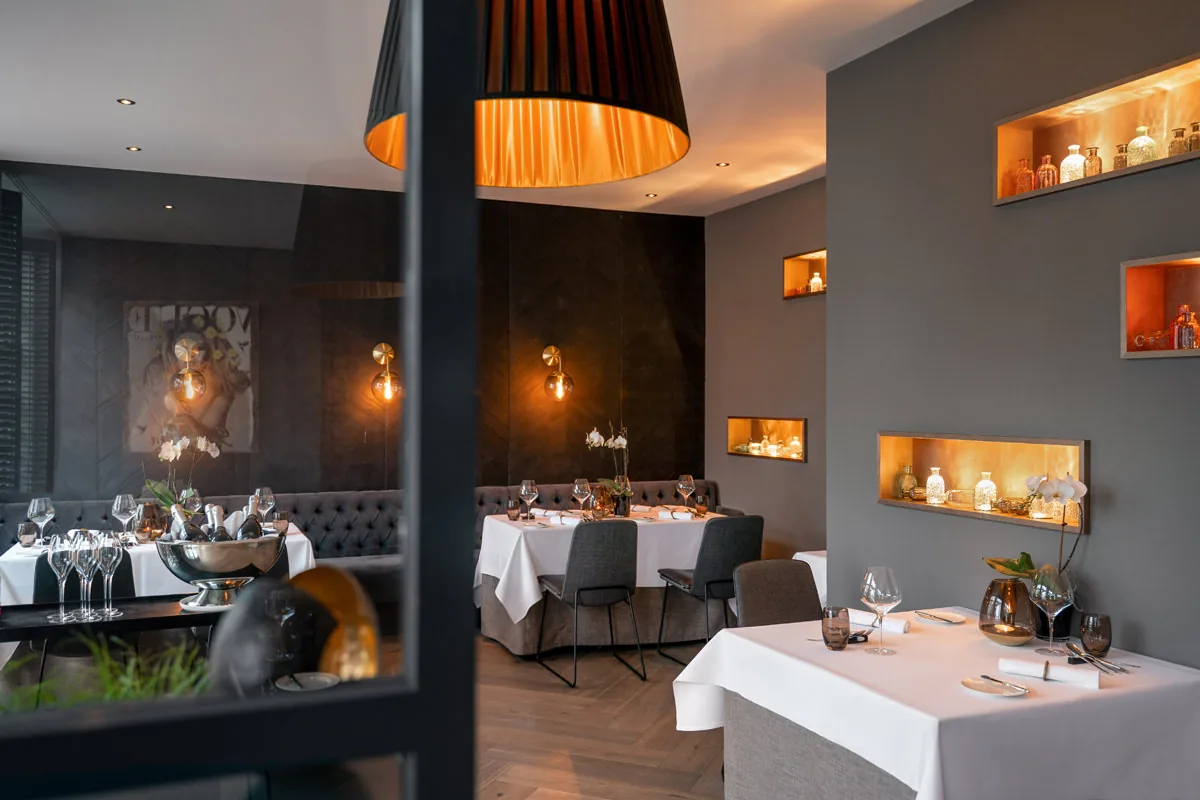 Restaurant mit weiß eingedeckten Tischen und warm beleuchteten Wandnischen