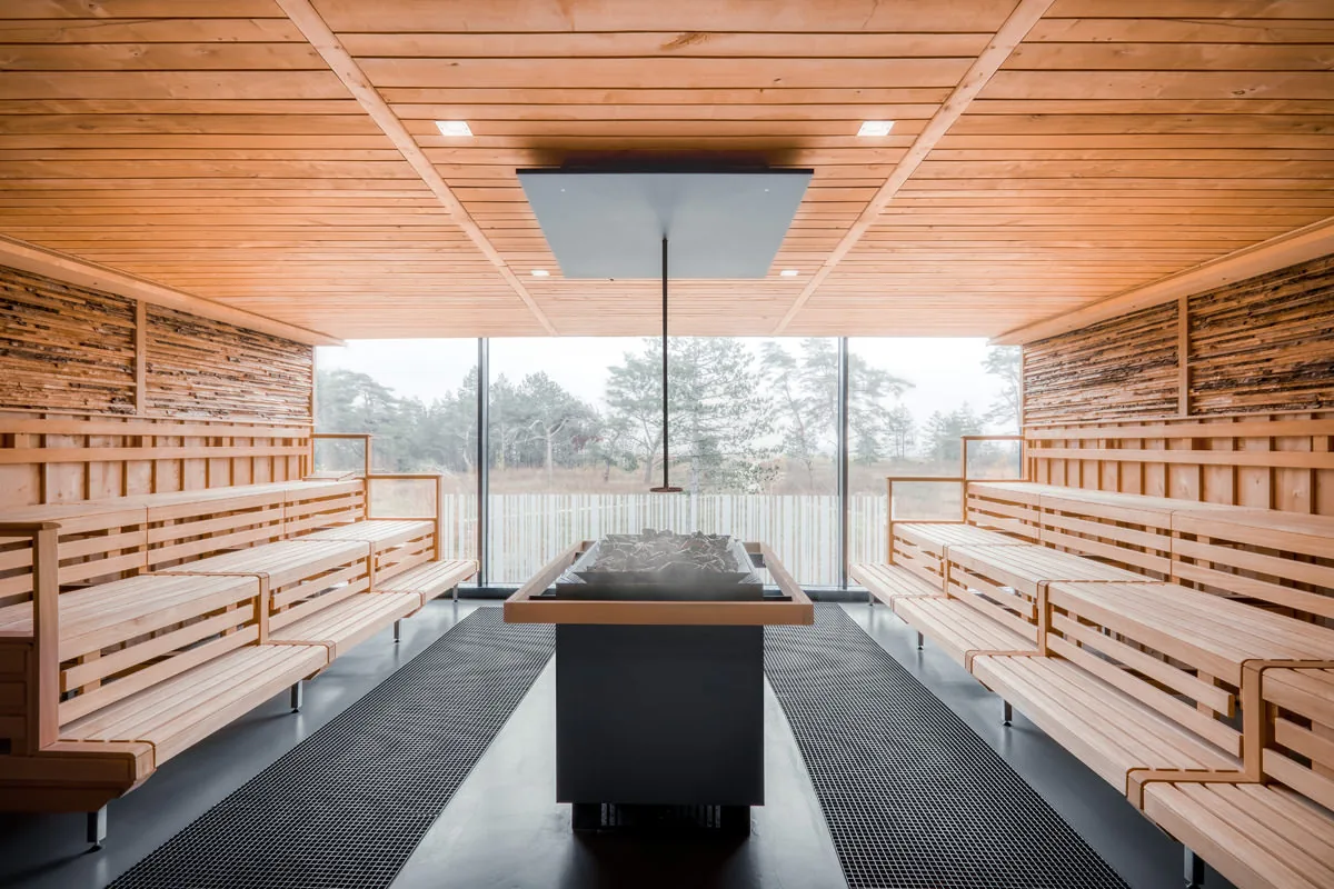 Große Sauna mit Panoramafenster ins Grüne, umlaufenden Holzbänken und Aufgussofen