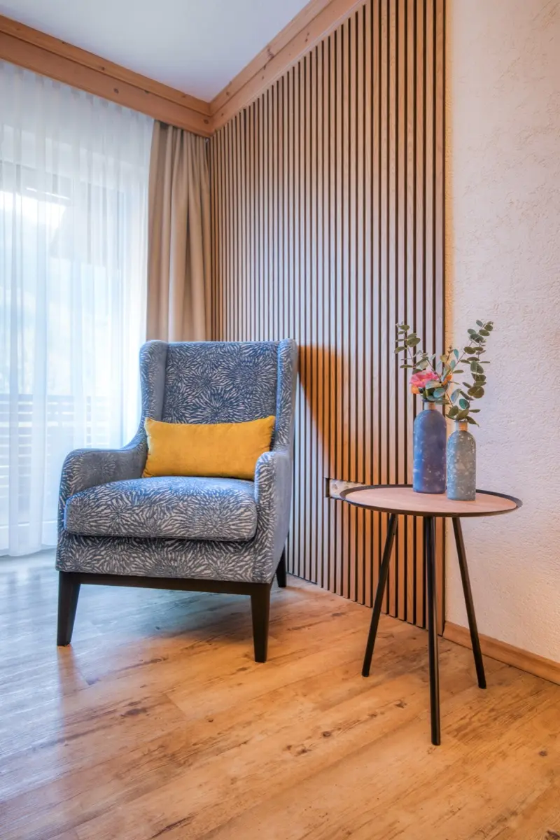 Armchair in front of a wall of pale timber slats, a side table next to it