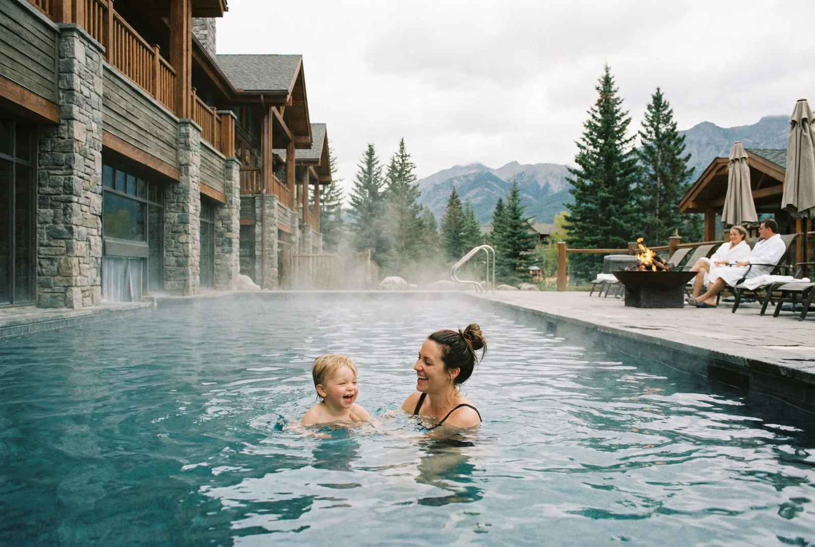 Mother and child in the steaming outdoor pool of a wellness hotel against a mountain backdrop