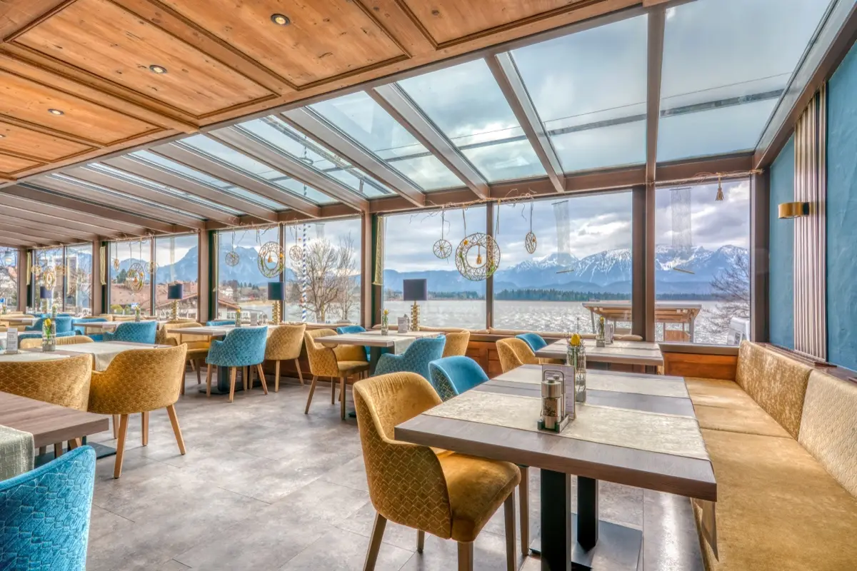 Laid tables in the conservatory in front of an alpine panorama behind the glass front